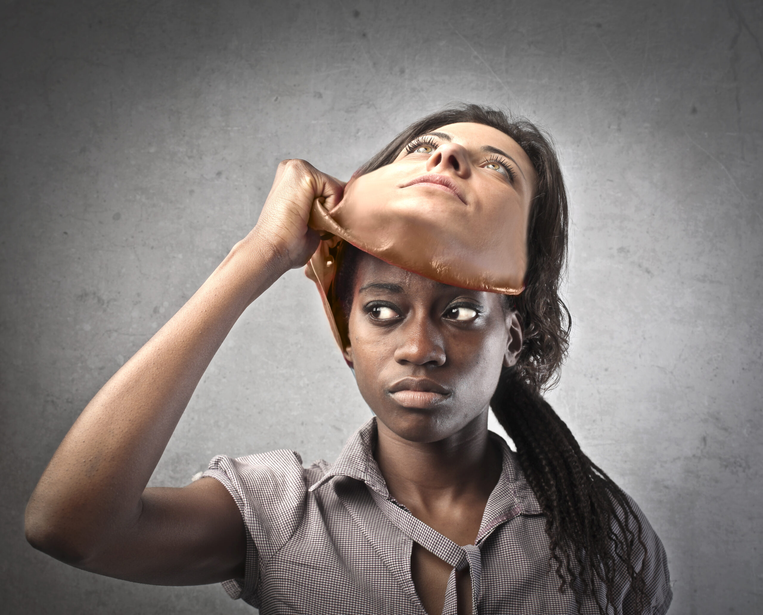 An African-American woman peels off a mask of a white woman, demonstrating code-switching as the result of racial or cultural bias.
