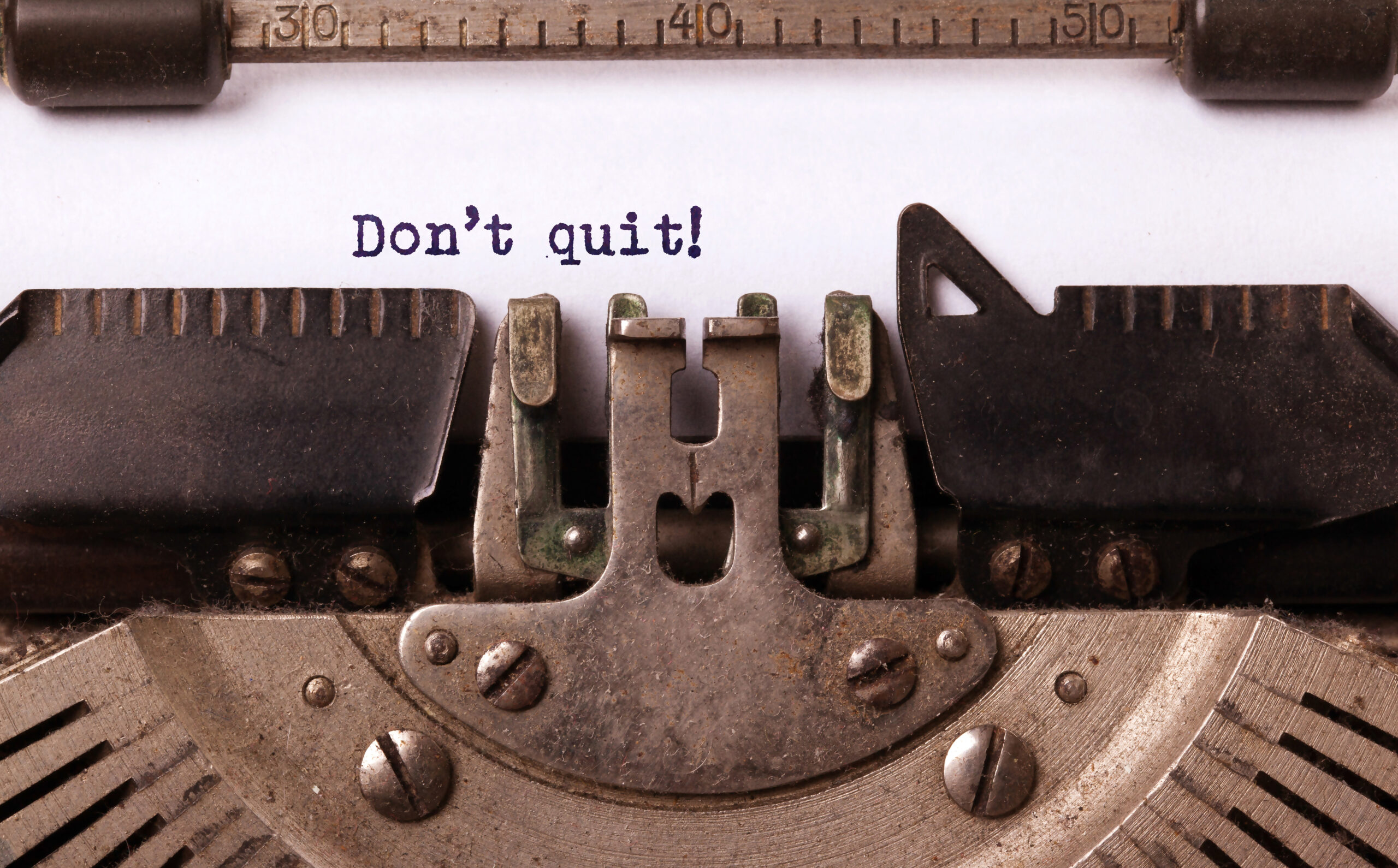 The words "don't quit" are written on paper in a typewriter. Don't just quit whenever you feel like quitting.