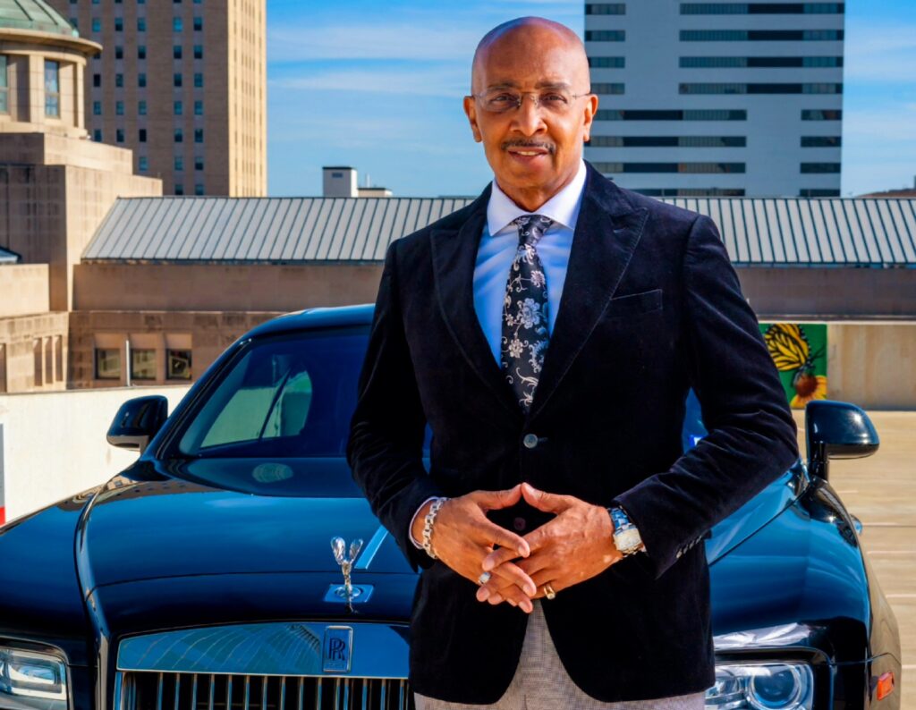 Dr. D standing in front of a black Rolls-Royce in a suit and tie. Figuring out what makes your business unique helps you stand out in an effective way (as Dr. D does here).