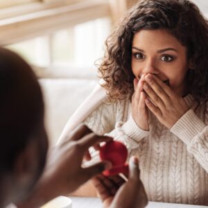 Brown-Skinned Woman With Curly Hair in Light Brown Sweater and Brown-Skinned Man- Surprise Marriage Engagement Red Box