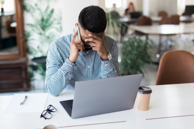 Man sitting with his hands pinching his brow on the phone. The Cost of Your Prayers Being Answered Blessings, Burdens, and the Fire That Refines