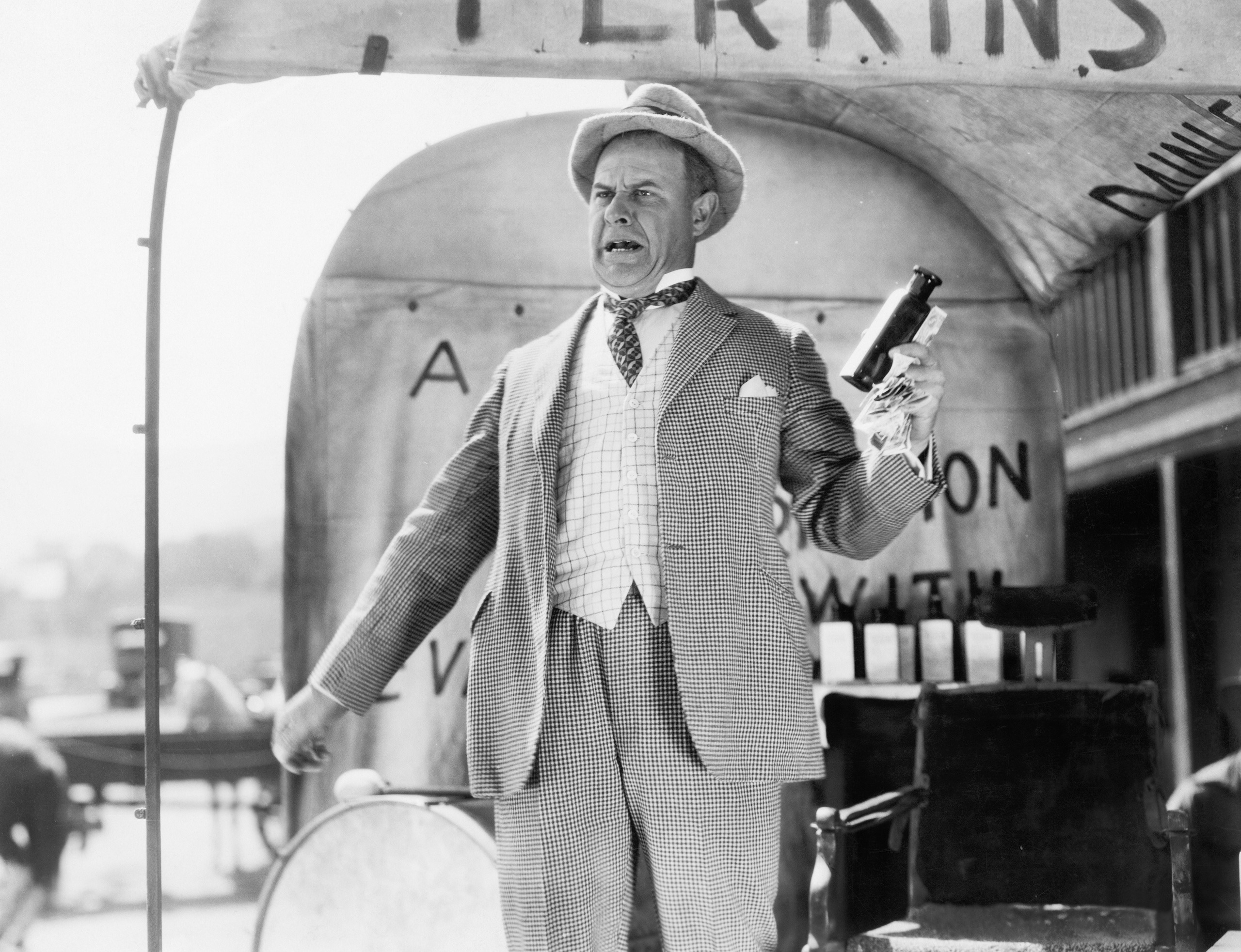 Conman is standing in front of a vintage cart selling fake cures. Blog by Dr. D Ivan Young, MCC on Building a Brand & the Credibility Crisis